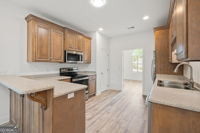 124 Cinder Hill Dr, Brunswick, GA 31523 - kitchen featuring stainless steel appliances, a sink, light wood-style floors, a peninsula, and baseboards