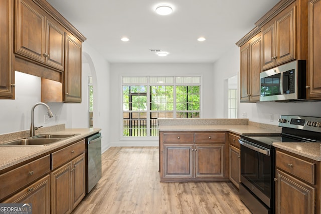 124 Cinder Hill Dr, Brunswick, GA 31523 - kitchen featuring appliances with stainless steel finishes, a sink, light wood-type flooring, a peninsula, and light countertops