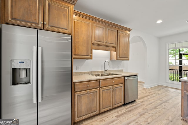 124 Cinder Hill Dr, Brunswick, GA 31523 - kitchen featuring stainless steel appliances, a sink, arched walkways, light wood-type flooring, and light countertops