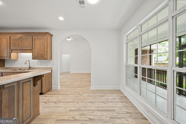 124 Cinder Hill Dr, Brunswick, GA 31523 - kitchen featuring arched walkways, baseboards, light wood-type flooring, recessed lighting, and brown cabinetry