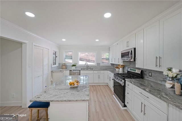 9460 Chestatee Ct, Gainesville, GA 30506 - kitchen with appliances with stainless steel finishes, crown molding, light wood-style floors, backsplash, and white cabinetry