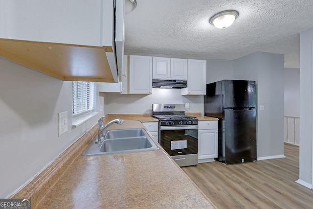 5295 Old Trail Cir, Stone Mountain, GA 30088 - kitchen with stainless steel range with gas stovetop, freestanding refrigerator, under cabinet range hood, white cabinets, and light wood-style floors