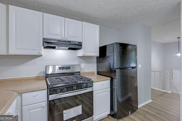 5295 Old Trail Cir, Stone Mountain, GA 30088 - kitchen featuring stainless steel gas range, freestanding refrigerator, under cabinet range hood, light wood finished floors, and white cabinets