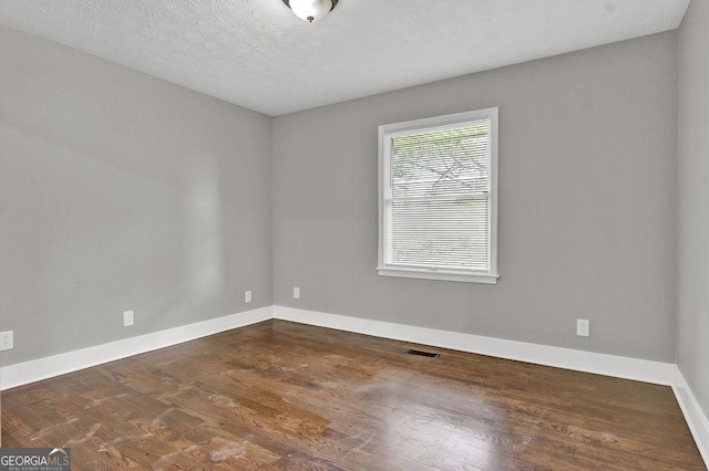 empty room featuring dark wood-style floors, baseboards, and a textured ceiling