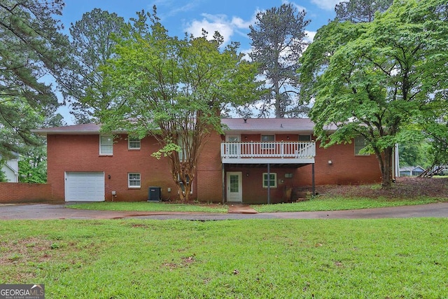 rear view of property with driveway, a garage, central air condition unit, and a lawn