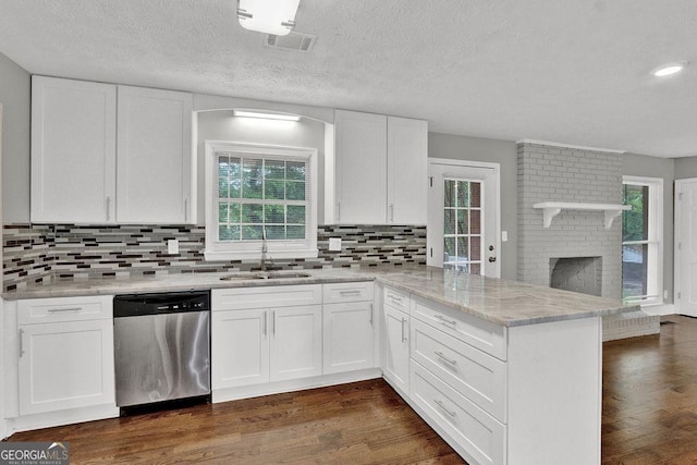 kitchen with stainless steel dishwasher, a sink, a peninsula, backsplash, and a textured ceiling