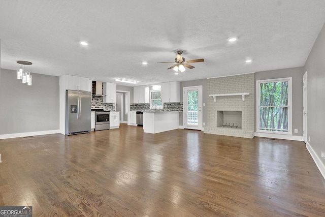 unfurnished living room featuring a ceiling fan, baseboards, healthy amount of natural light, recessed lighting, and a textured ceiling