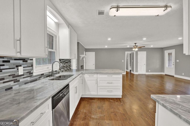 kitchen featuring dishwasher, a sink, a peninsula, tasteful backsplash, and white cabinetry