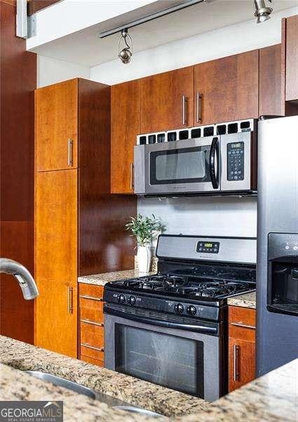964 Dekalb Ave NE Unit 112, Atlanta, GA 30307 - kitchen with stainless steel appliances, light stone countertops, and brown cabinets
