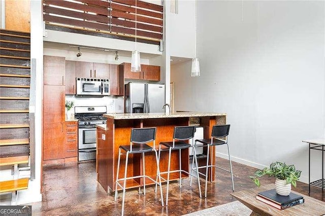 964 Dekalb Ave NE Unit 112, Atlanta, GA 30307 - kitchen featuring stainless steel appliances, a breakfast bar area, concrete flooring, baseboards, and track lighting