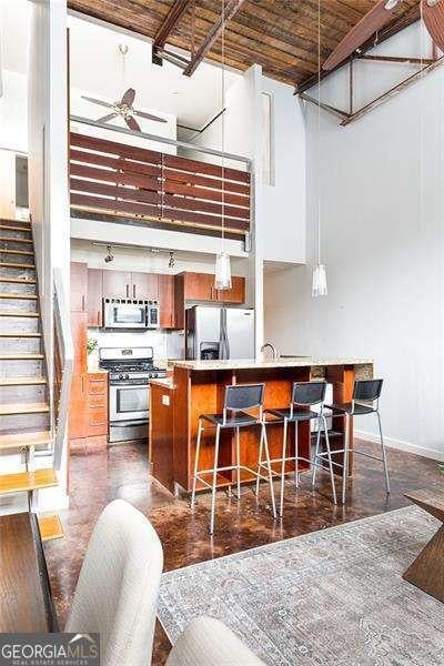 964 Dekalb Ave NE Unit 112, Atlanta, GA 30307 - kitchen featuring stainless steel appliances, a high ceiling, ceiling fan, baseboards, and a breakfast bar area