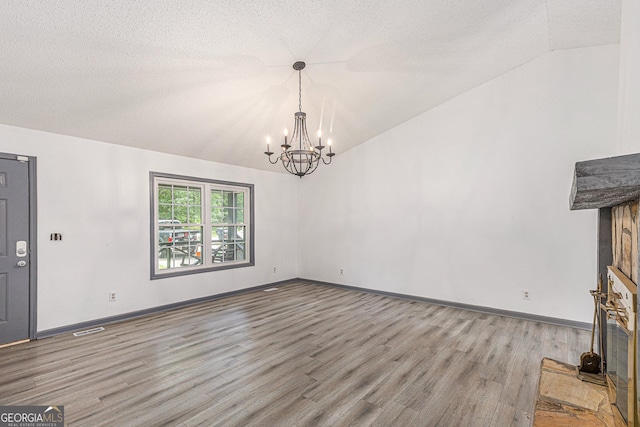 5406 Jamestowne Dr, Powder Springs, GA 30127 - unfurnished living room with lofted ceiling, a chandelier, wood finished floors, a textured ceiling, and baseboards