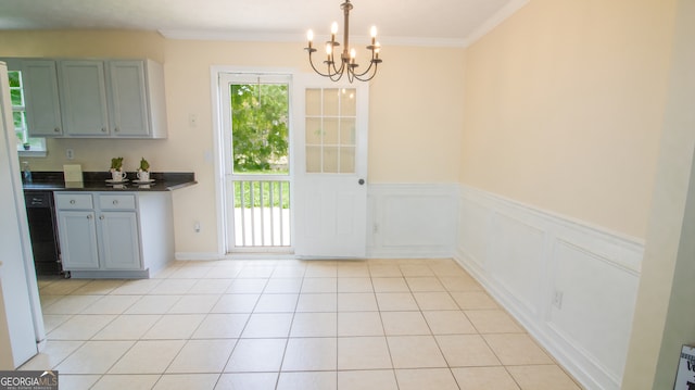 unfurnished dining area with a chandelier, crown molding, light tile patterned floors, and a wainscoted wall