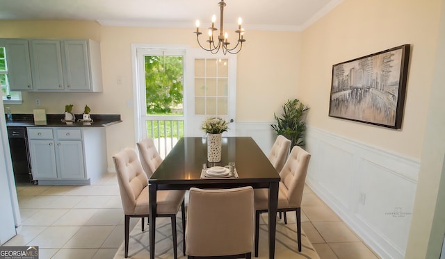dining room featuring a chandelier, light tile patterned floors, a wainscoted wall, and ornamental molding
