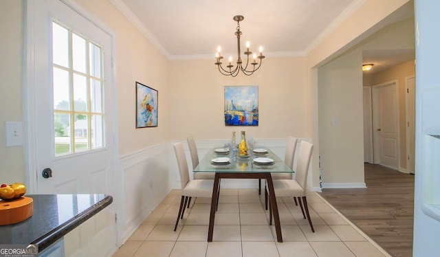 dining space featuring a chandelier, healthy amount of natural light, ornamental molding, wainscoting, and light tile patterned flooring