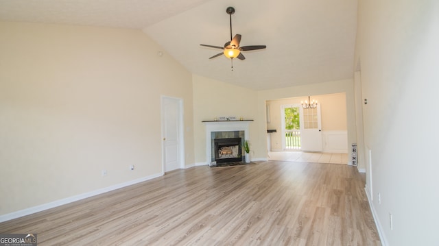 unfurnished living room with a chandelier, light wood-style floors, a tile fireplace, a ceiling fan, and high vaulted ceiling