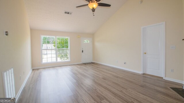 unfurnished living room with ceiling fan, wood finished floors, baseboards, and high vaulted ceiling