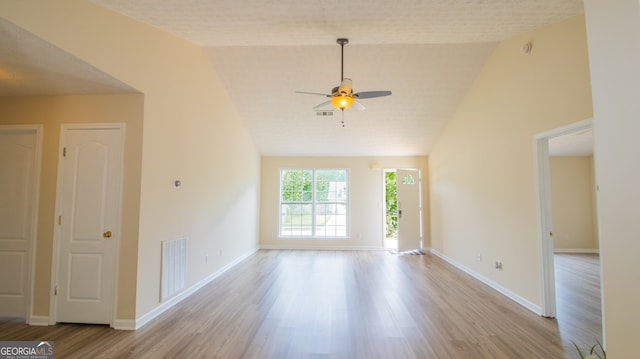 empty room with ceiling fan, wood finished floors, lofted ceiling, and baseboards