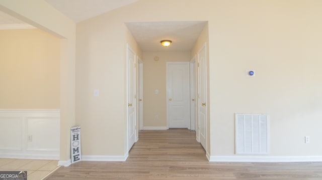 corridor featuring light wood finished floors and baseboards