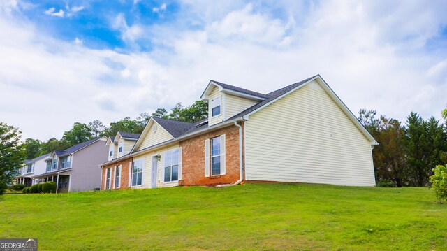 rear view of property featuring brick siding and a yard