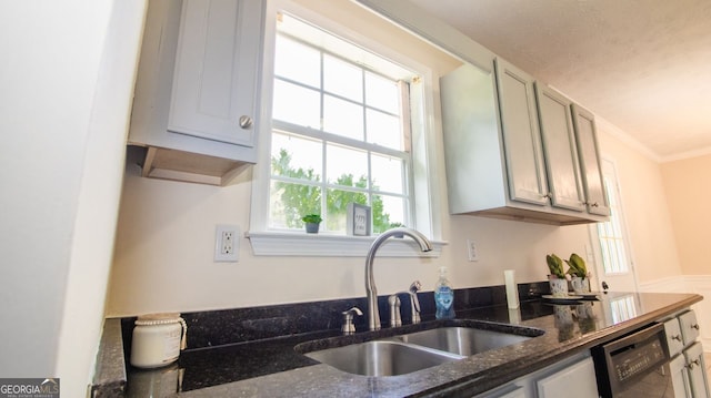 kitchen featuring a sink, black dishwasher, healthy amount of natural light, dark stone counters, and ornamental molding