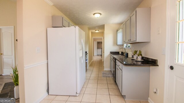 kitchen with white fridge with ice dispenser, a sink, light tile patterned floors, dishwasher, and baseboards