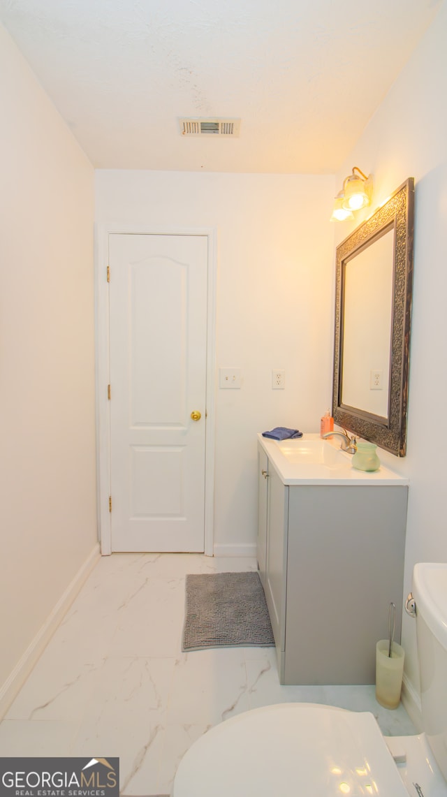 bathroom with toilet, baseboards, marble finish floors, and vanity