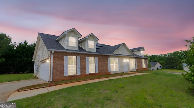view of front facade featuring brick siding, a front yard, driveway, and an attached garage
