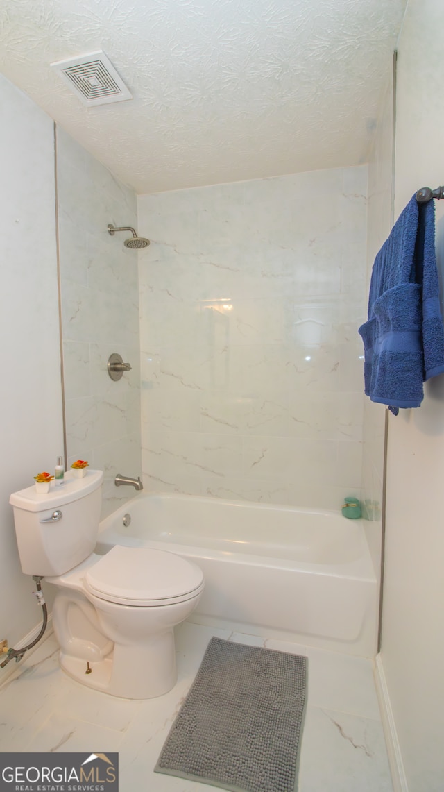 bathroom with marble finish floors, toilet,  shower combination, a textured ceiling, and baseboards