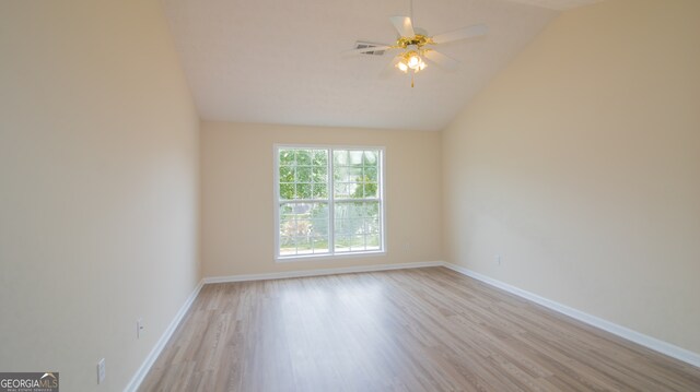 spare room with vaulted ceiling, light wood-type flooring, ceiling fan, and baseboards