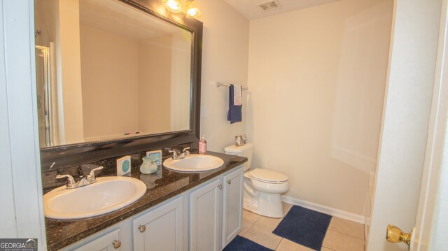 bathroom featuring toilet, tile patterned floors, and double vanity