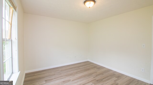 unfurnished room with light wood finished floors and baseboards