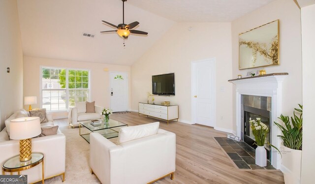 living room featuring a tile fireplace, wood finished floors, high vaulted ceiling, a ceiling fan, and baseboards