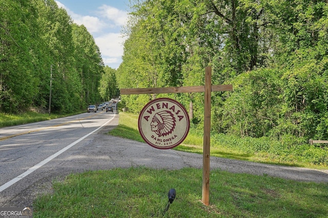 view of asphalt street featuring a wooded view