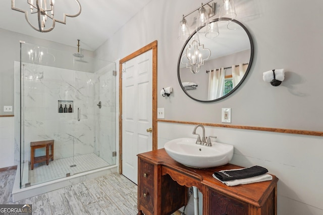 bathroom with a chandelier, a marble finish shower, and vanity