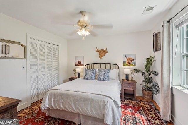 bedroom with wood finished floors, a closet, ceiling fan, and baseboards