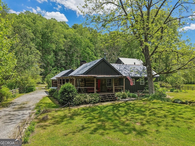 view of front of house featuring a porch, a front yard, driveway, and metal roof