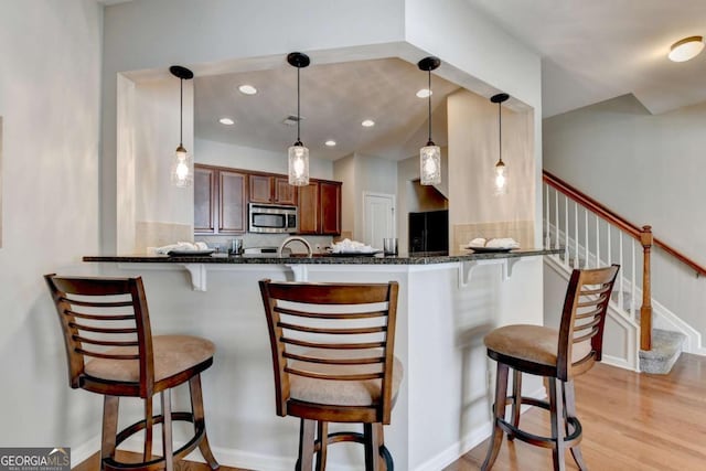 2505 Thackery Ct, Cumming, GA 30041 - kitchen with stainless steel microwave, black refrigerator with ice dispenser, a kitchen breakfast bar, light wood-style floors, and recessed lighting