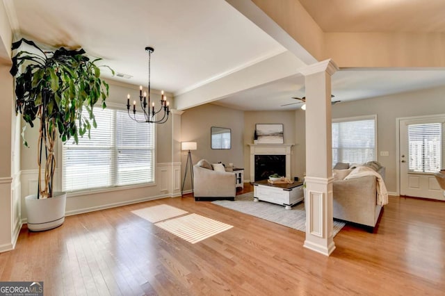 2505 Thackery Ct, Cumming, GA 30041 - living area with light wood-style flooring, ceiling fan, a fireplace, a wainscoted wall, and a chandelier