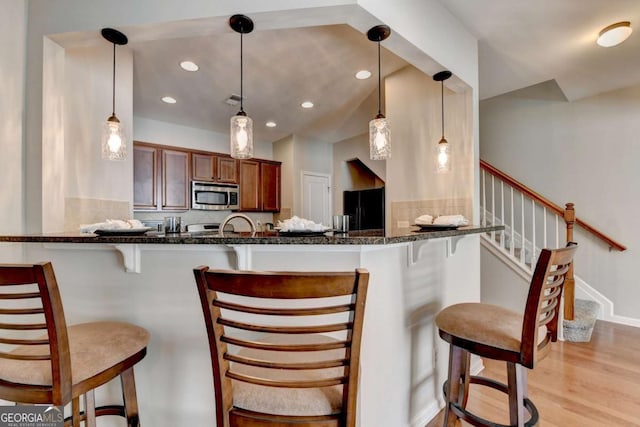 2505 Thackery Ct, Cumming, GA 30041 - kitchen with stainless steel microwave, freestanding refrigerator, a breakfast bar, light wood-style flooring, and recessed lighting