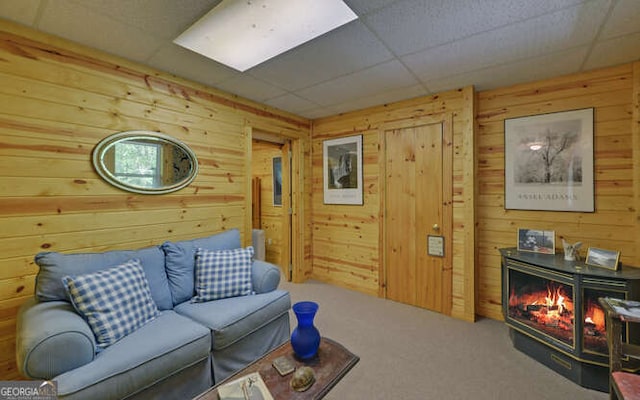 living room featuring wooden walls, a drop ceiling, and carpet floors