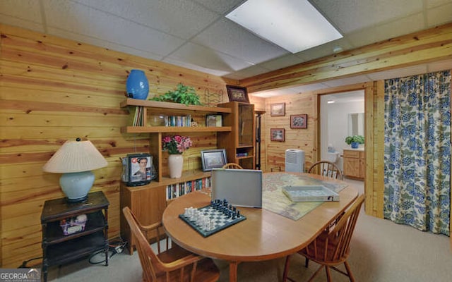 dining room featuring wood walls and a drop ceiling