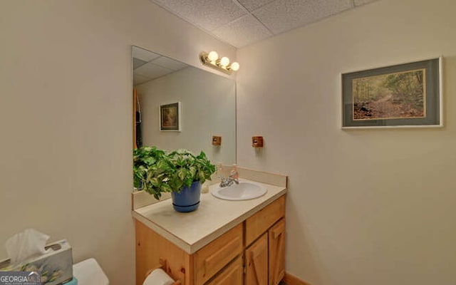 half bath featuring a drop ceiling and vanity