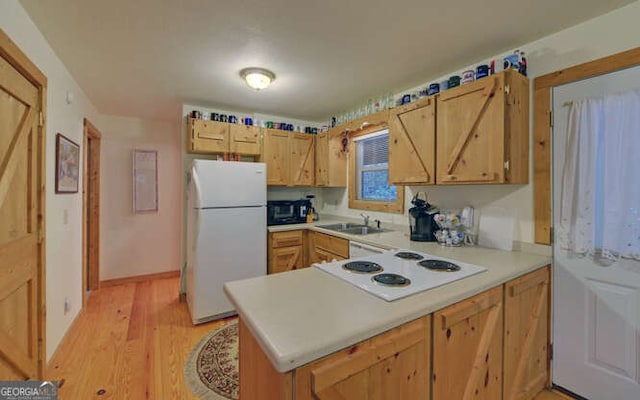 kitchen with white appliances, a sink, light countertops, and light wood-style flooring