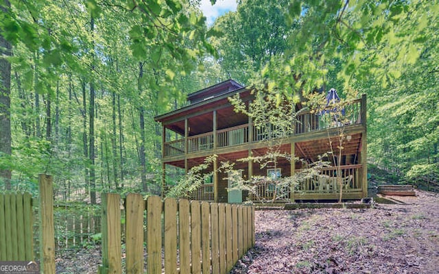 rear view of property featuring a deck and fence