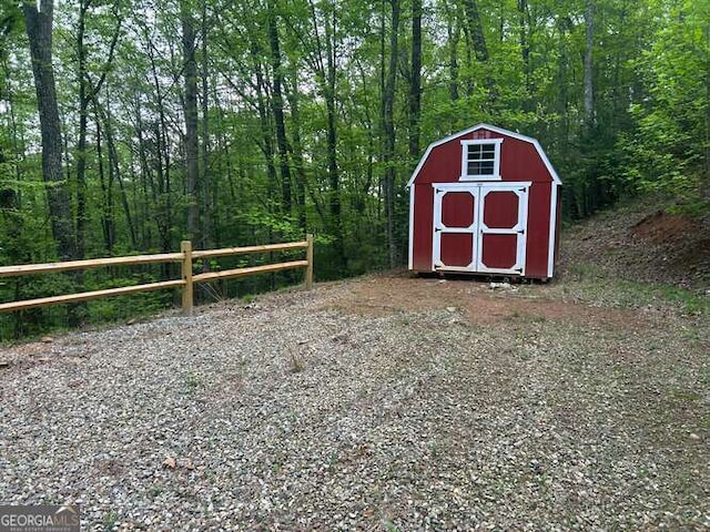 view of shed featuring fence and a wooded view