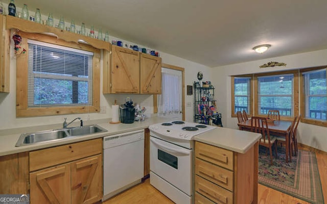 kitchen with white appliances, a sink, a peninsula, and light wood-style flooring