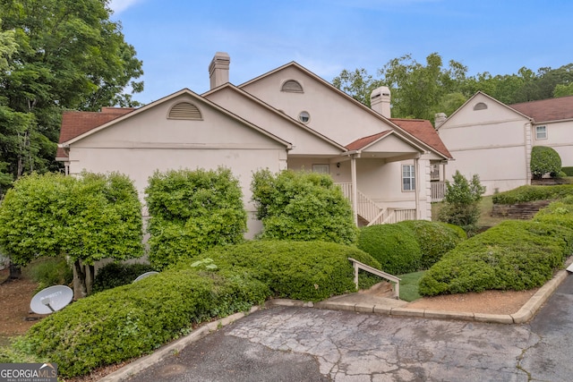 view of front of house featuring a chimney, stucco siding, and stairs