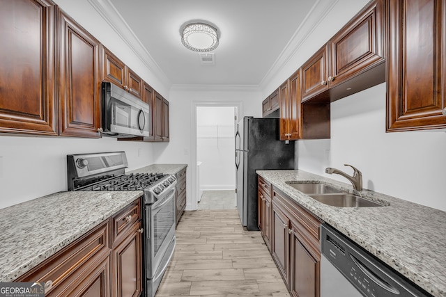 kitchen featuring stainless steel appliances, a sink, light wood-style flooring, crown molding, and light stone countertops