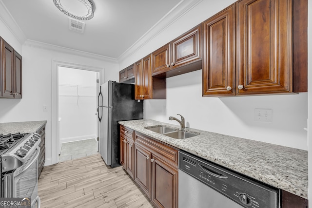 kitchen with a sink, stainless steel appliances, ornamental molding, light wood-style flooring, and light stone countertops